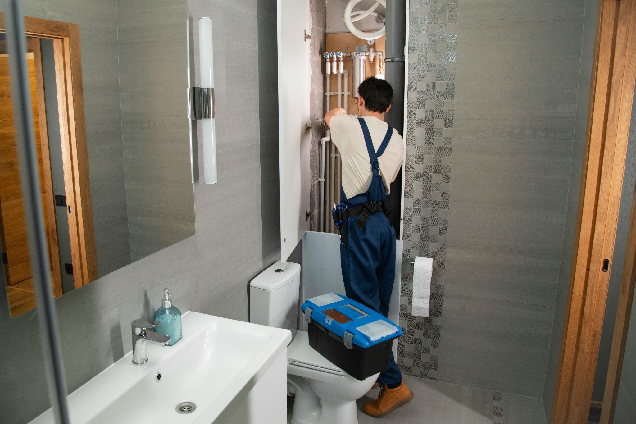 A plumber works on bathroom pipe fittings to provide reliable service as a plumber in Los Banos.